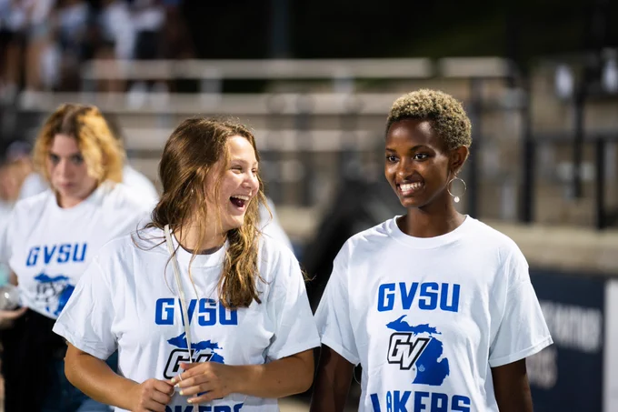 Two students smile while wearing GVSU Lakers shirts. 