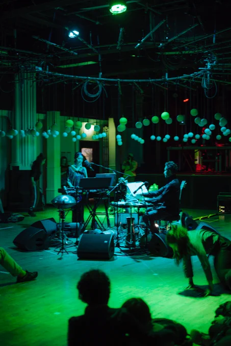 Musicians are in the centre of a circle of orbs performing as green light glows around them 