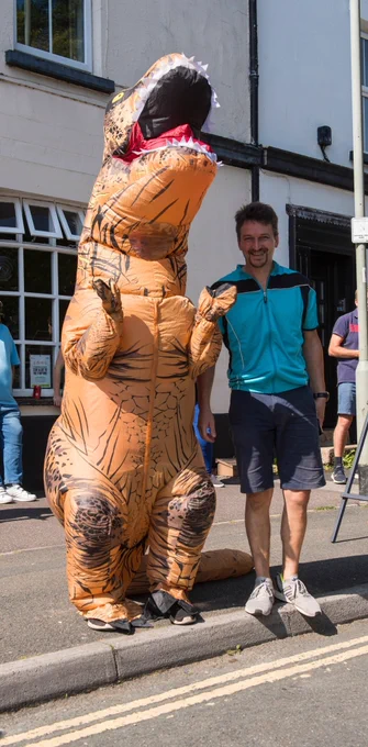 two fans, one dressed in a dinosaur suit. 