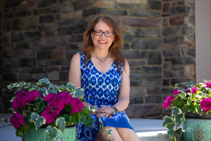 Woman sits on porch surrounded by flowers