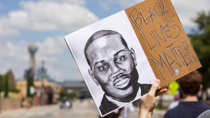 A photo of a poster that says "Black Lives Matter" and shows a picture of Ahmaud Arbery.