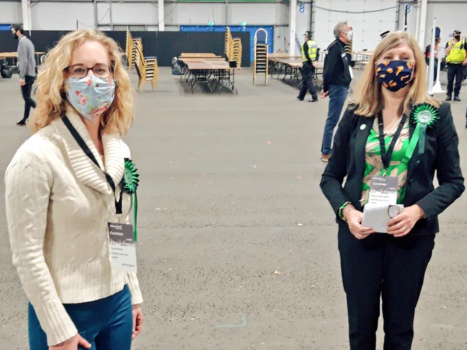 Lorna Slater and Alison Johnstone wearing green rosettes and facemasks.