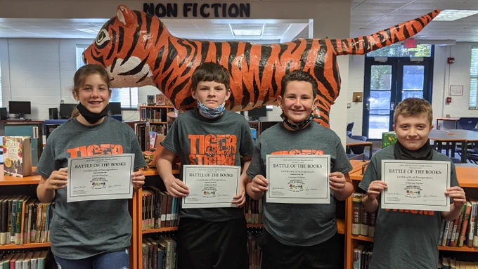Four students from Randleman Middle School holding up certificates from the Battle of the Books Competition.