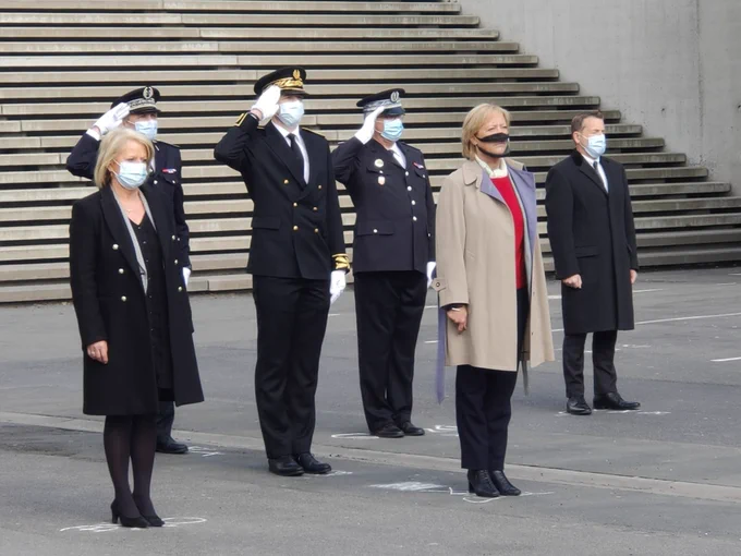 Brigitte Bourguignon et Sophie Cluzel, secrétaire d'État chargée des personnes handicapées sont au premier plan. 
Derrière elles, le préfet en uniforme officiel et deux autres hommes en uniforme font un salut militaire.