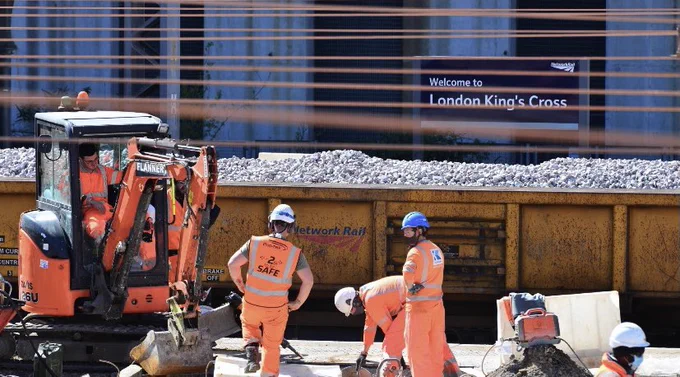 Engineers work on one of the platforms at London Kings Cross Station in front of an engineering train full of new ballast.