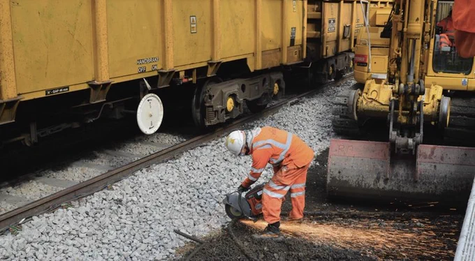An engineer uses a cutter to cut through a redundant metal pipe down on the tracks at London Kings Cross Station, causing sparks to fly up.