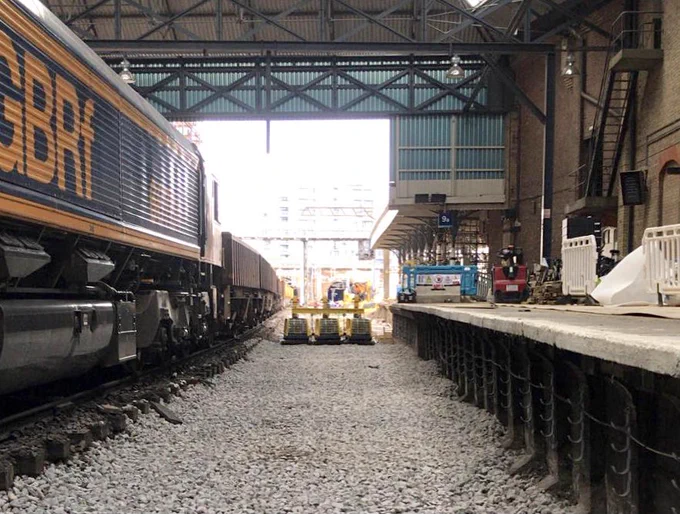 Newly laid ballast on platform nine at London Kings Cross Station with machines called wackers which are used to flatten the ballast down in the background and an engineering train on the left.