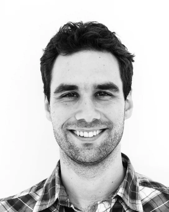 A black and white photo of a man in a plaid shirt. 