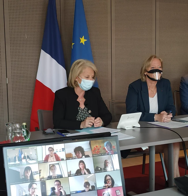 Salle de réunion. 
Au premier plan, un écran diffusant 12 caméras de personnes invitées à la réunion. 
Au second plan, de gauche à droite, Mme Brigitte Bourguignon, ministre déléguée auprès du ministre des solidarités et de la santé, chargée de l'autonomie et Mme Sophie Cluzel secrétaire d'État chargée des personnes handicapées.
À l'arrière plan, le drapeau français et le drapeau européen.