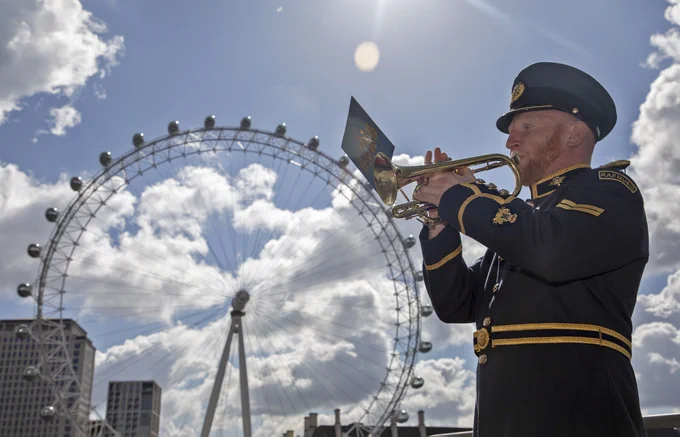 Image shows RAF Music Services trumpeter playing with the London Eye behind him.