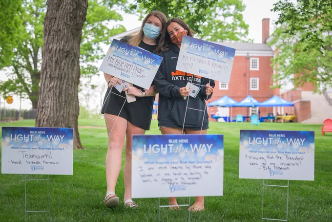 Two students hold their Light the Way signs sharing their accomplishments and aspirations from the last year