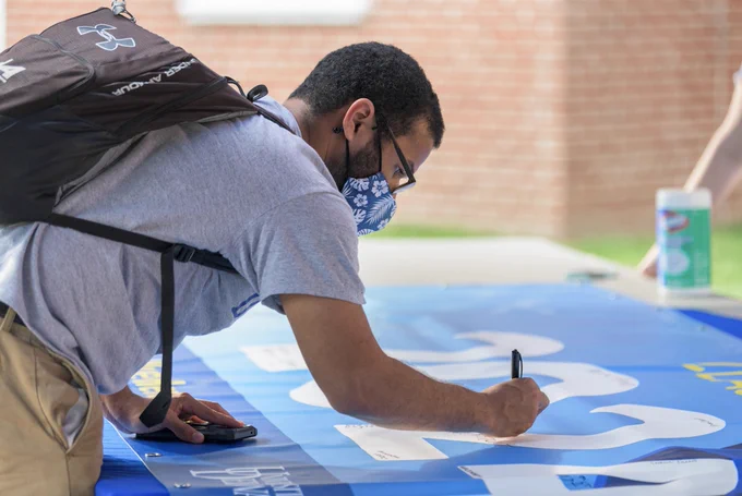A student signs his Class of 2024 class banner