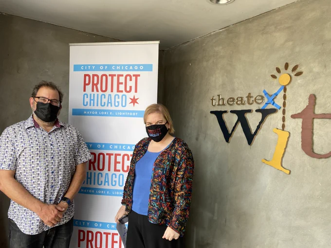 Dr Arwady and Jeremy Wechsler standing in front of Protect Chicago and Theater Wit signs
