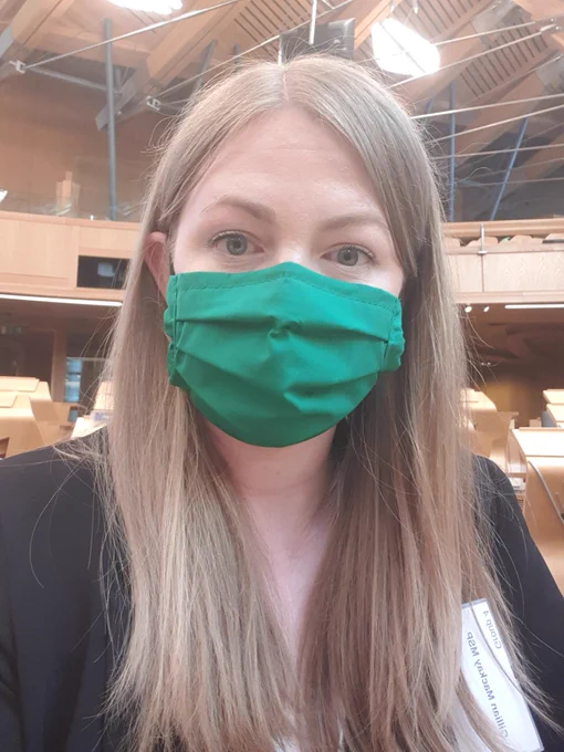 Photo of Gillian with a green face mask on in the chamber at the Scottish Parliament.