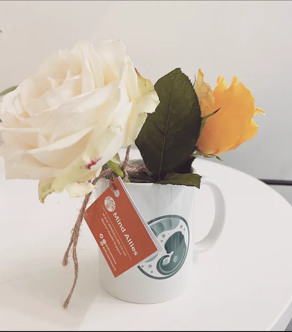 Two roses in a lab-branded mug, with a tag for Mind Allies