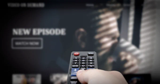 (Alt="person pointing a TV remote at the TV. TV in the background with on demand TV, with the words new episode.")