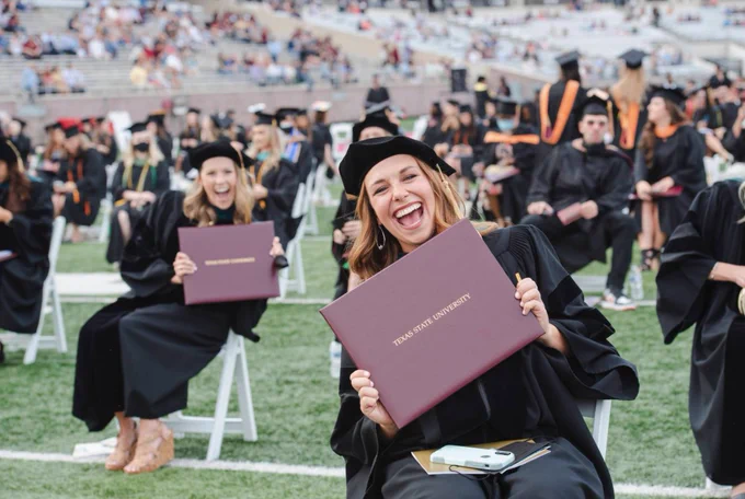 Texas State University Bobcat Stadium Spring 2021 Graduation Two Students Seated with Diplomas