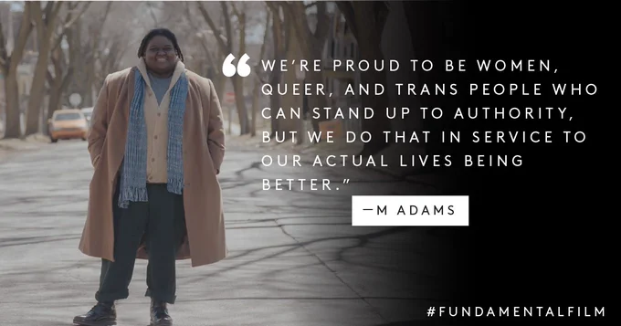 Text: "We're proud to be women, queer, and trans people who can stand up to authority, but we do that in service to our actual lives being better." M Adams, #FundamentalFilm
Image: M Adams stands in a Madison, WI street, with a big smile and wearing a long winter coat. 