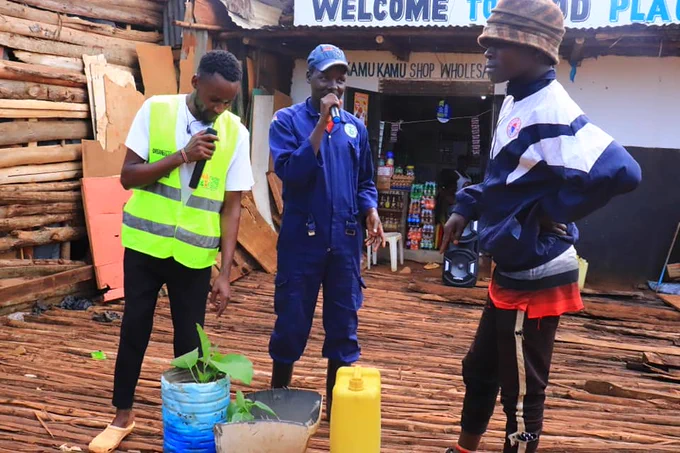 A young man showing plants grown in plastic bottles