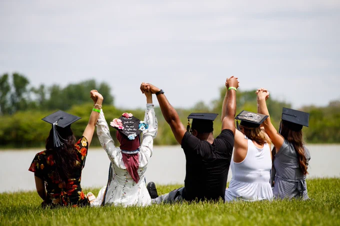 Photo of GSU students sitting on the grass by the lake holding hands in the year.