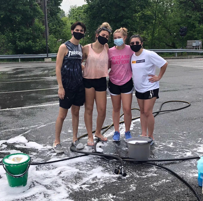 Photo of four students from the Washingtonville High School junior class, helping at the senior class car wash.