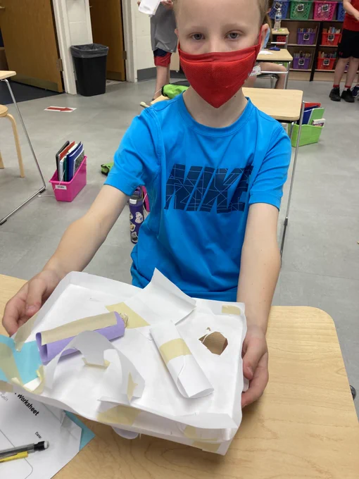 Fourth grader and the paper maze he designed.