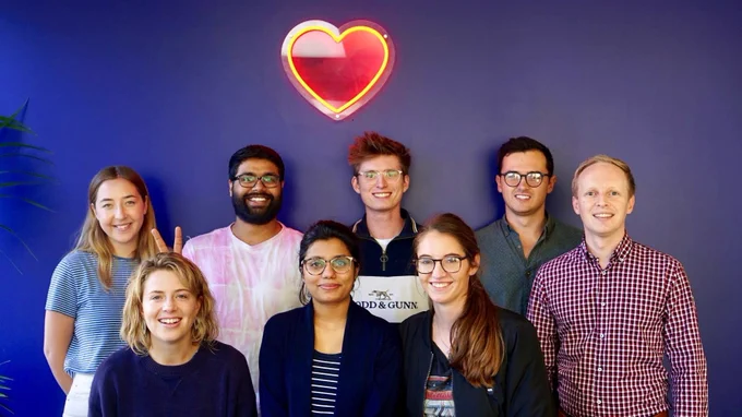 The HeartLab team standing in front of a heart shaped wall light.