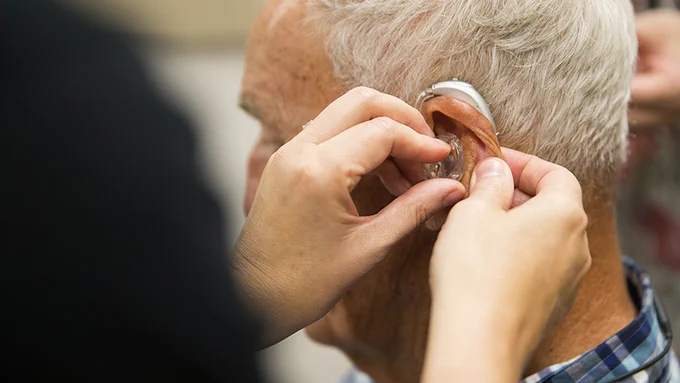 A gentleman is fitted with a hearing aid at the Barkley Speech Language and Hearing Clinic.