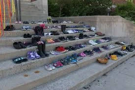 7 steps in a staircase hold 215 pairs of shoes to honour the students who died while in the care of a residential school in British Columbia. 