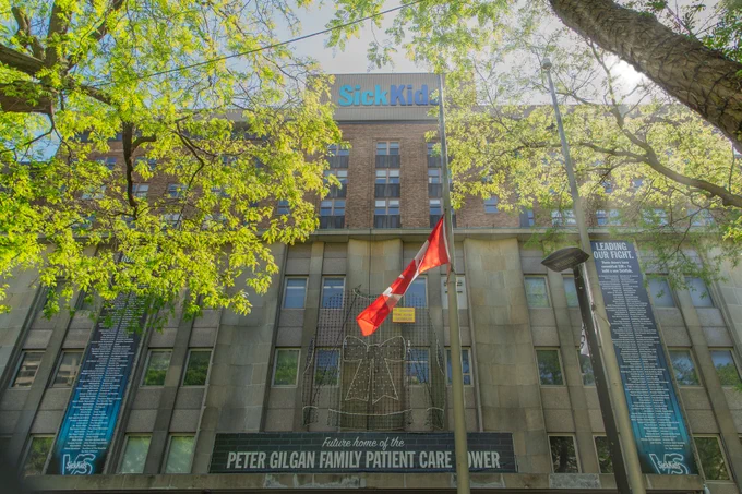 Canadian flag flying at half mast in front of SickKids building.