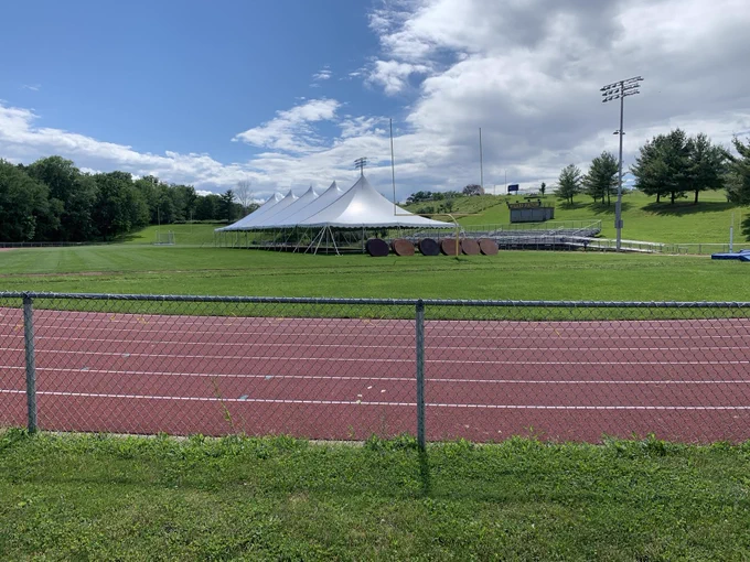 IMAGE of Football Field and Track with a tent up and tables nearby.