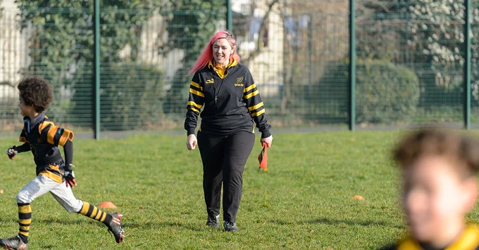 Female coach walking. One child running