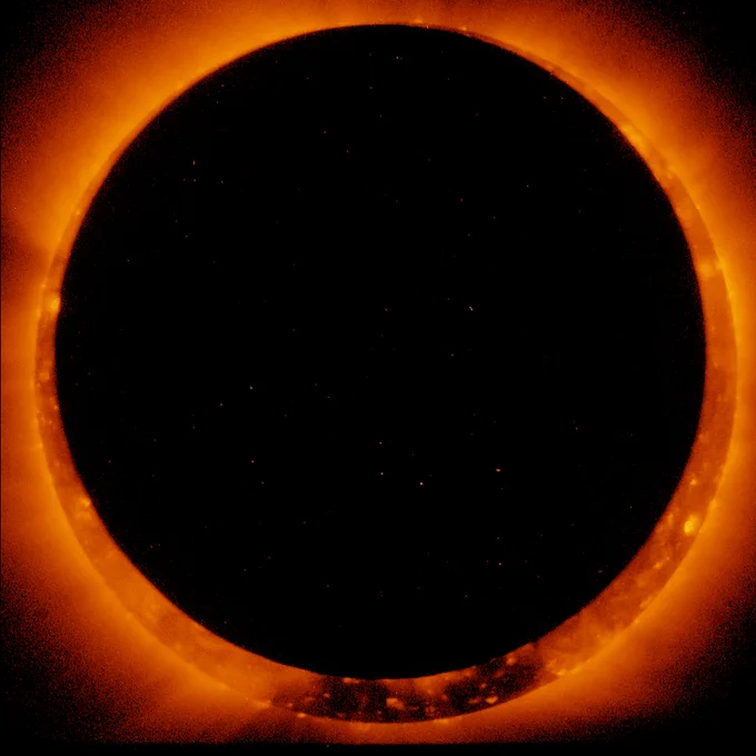 Black circle in front of larger, fiery red circle. 