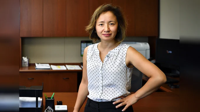 Yan Huang stands, facing forward, in an office