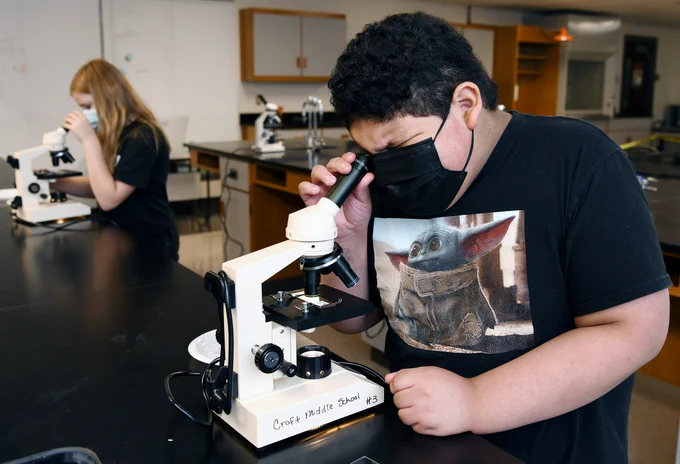 students looking through microscopes in class