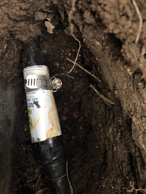 Aluminum cylinder compressed around a black pipe using a hose clamp.
