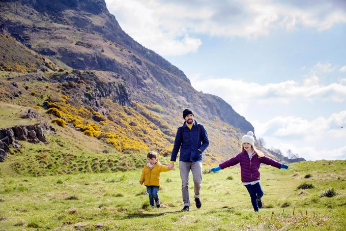 A man and two children walk in Holyrood Park