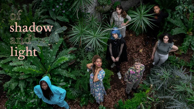 PACE cohort photographed from above in the Barbican Conservatory, all looking up standing surrounded by plants and trees.