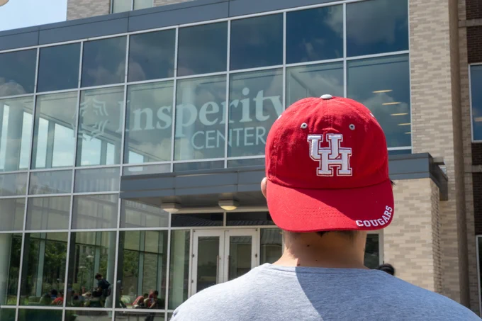 Young male in red baseball hat in front of building. 