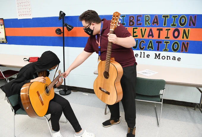guitar class. teacher helping student