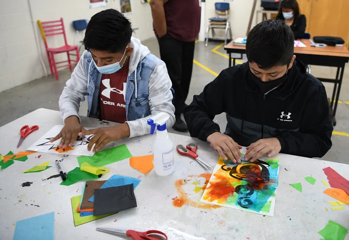 two students doing art in a classroom.