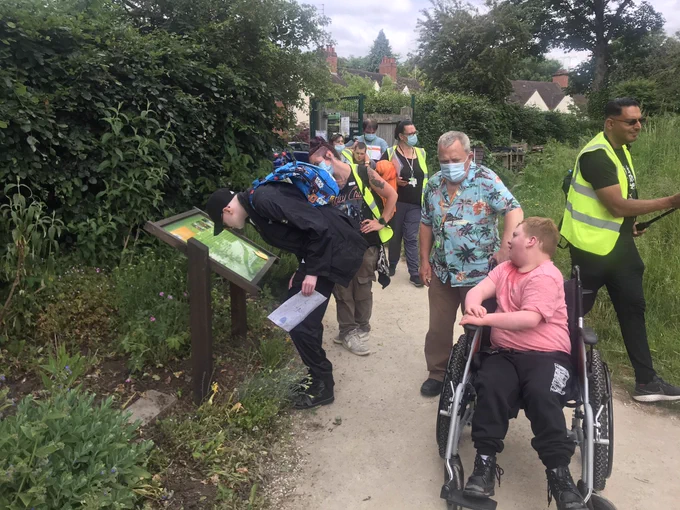 A group of people read a sign about nature in a sensory garden