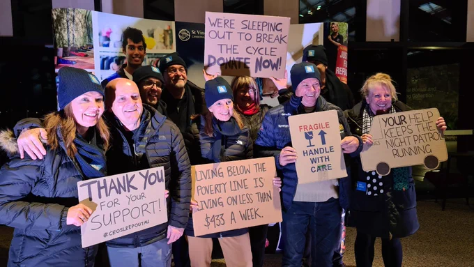 Synergy partners holding up signs to support the CEO Sleepout in the cold Canberra evening