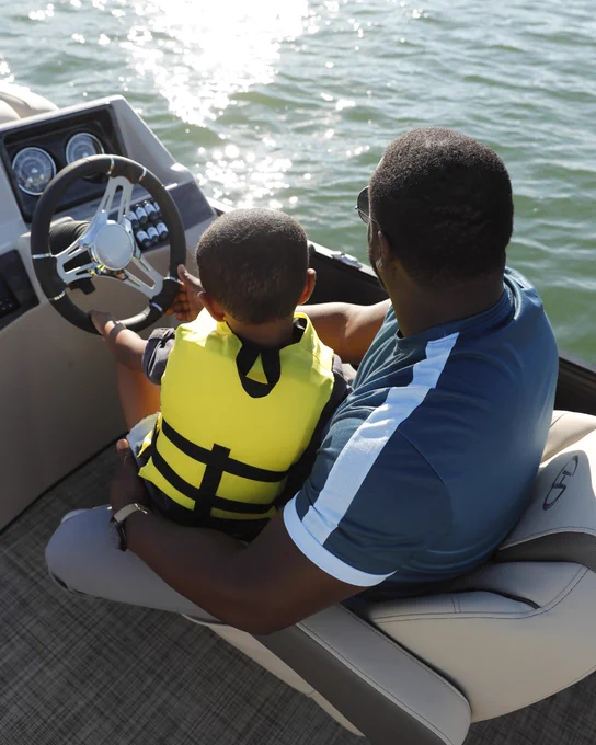 Father and son sitting on a Harris Pontoon Boat