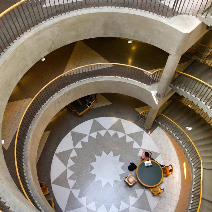 overhead shot of a spiral stairwell with students studying in a group at a desk below