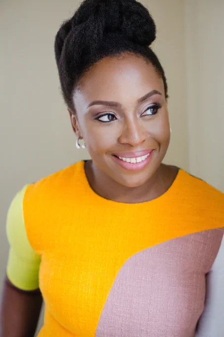 Author Chimamanda Ngozi Adichie smiling in a yellow dress