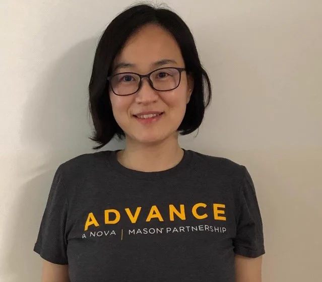 ADVANCE Coach poses for a photo. She is wearing a grey t-shirt with the ADVANCE logo on it. 