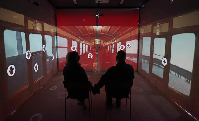 A couple hold hands on a virtual trip on the Liverpool Overhead Railway