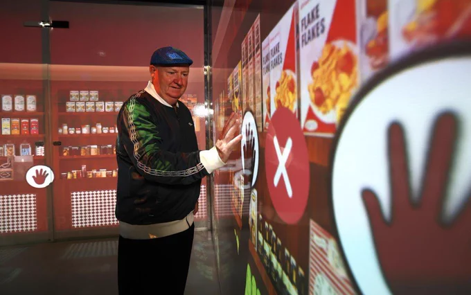 A digital replica of a typical 1950s shop depicting packets of cornflakes and other grocery goods