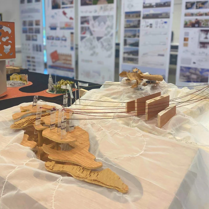 Photo of a 3d model struture in front of final year project posters.
